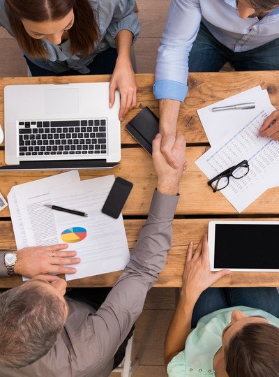 Rencontre : réunion business autour d'une table en bois massif avec ordinateur, tablette, notes et calculatrice.